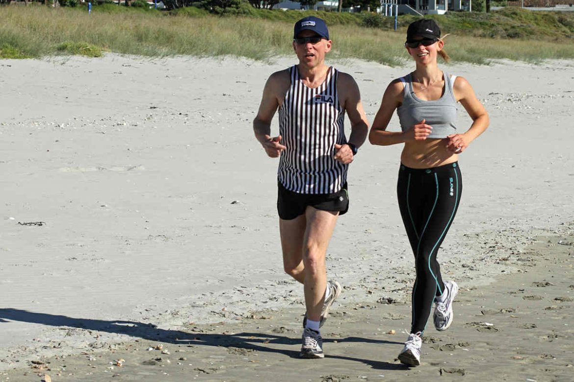 Un hombre y una mujer corriendo por la arena de la playa