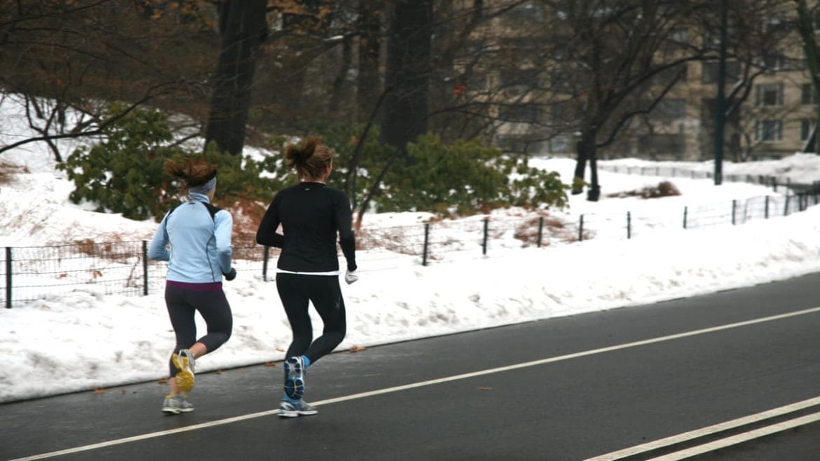 Pareja corriendo con frío y nieve