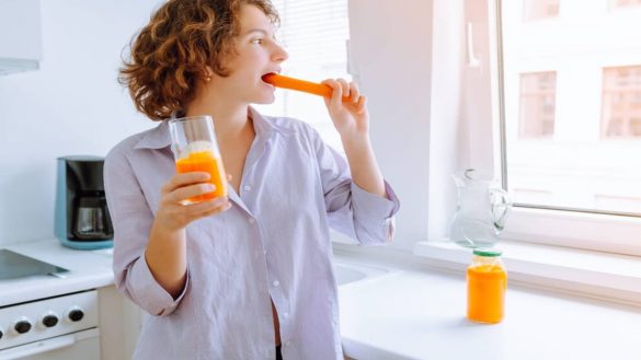 Mujer comiendo una zanahoria para mejorar la vitamina D
