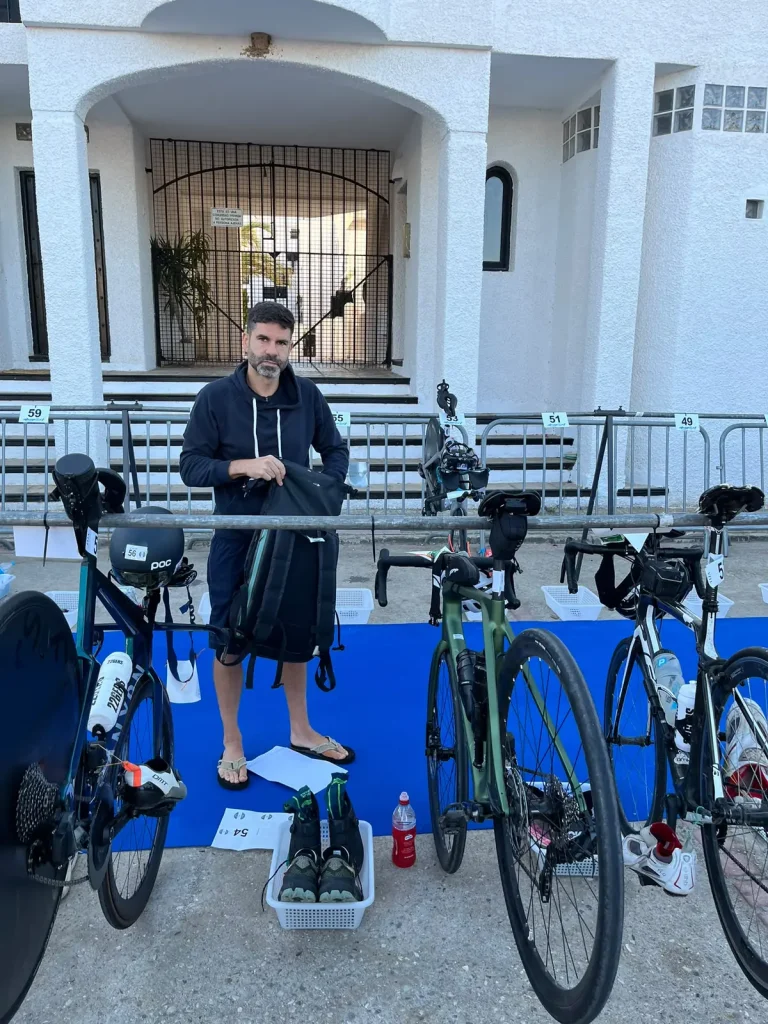 Pablo en la zona de transición antes de la salida, en chanclas, preparando su material junto a la bici.