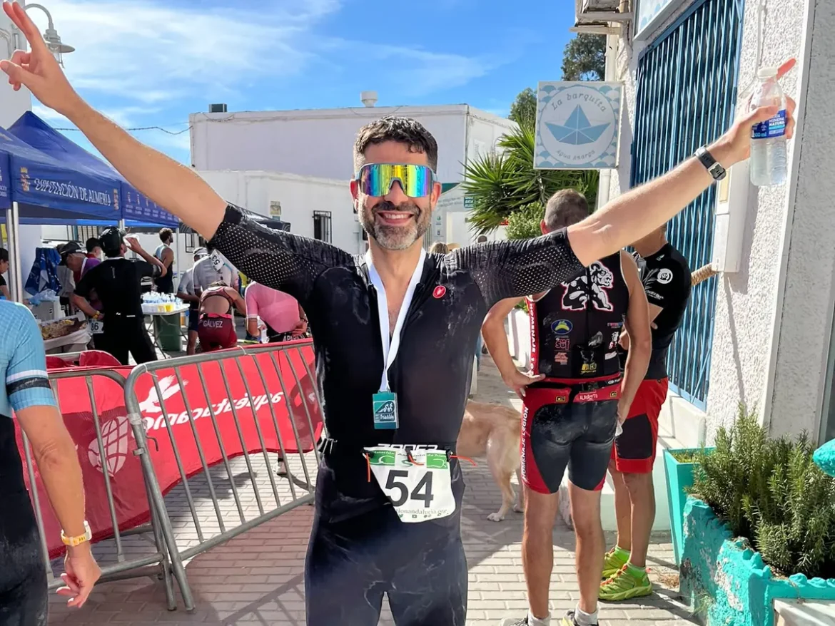 Pablo Caño en la meta del Triatlón Cabo de Gata, con los brazos abiertos, tritraje negro, dorsal 54 y la medalla al cuello, en Agua Amarga.